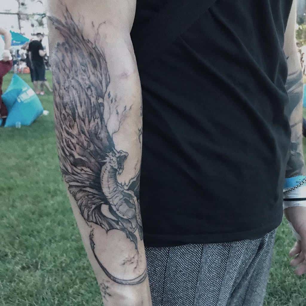 Close-up of a person's arm with a detailed dragon tattoo in an outdoor setting