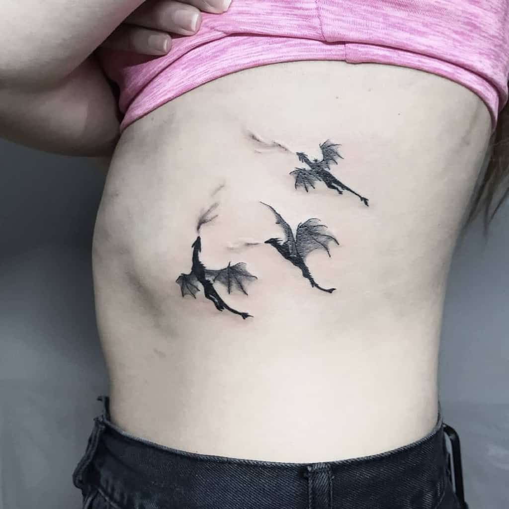 Tattoo of three flying dragons on a woman's side rib area