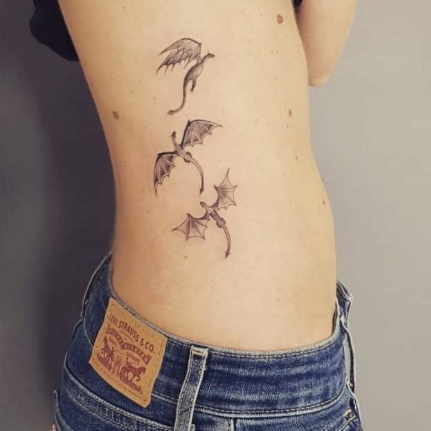Side tattoo of three small dragons, each in a different flying pose