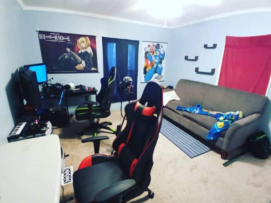 Room with gaming chairs, desk, computer setup, sofa, anime posters on walls, and a shelf with collectibles