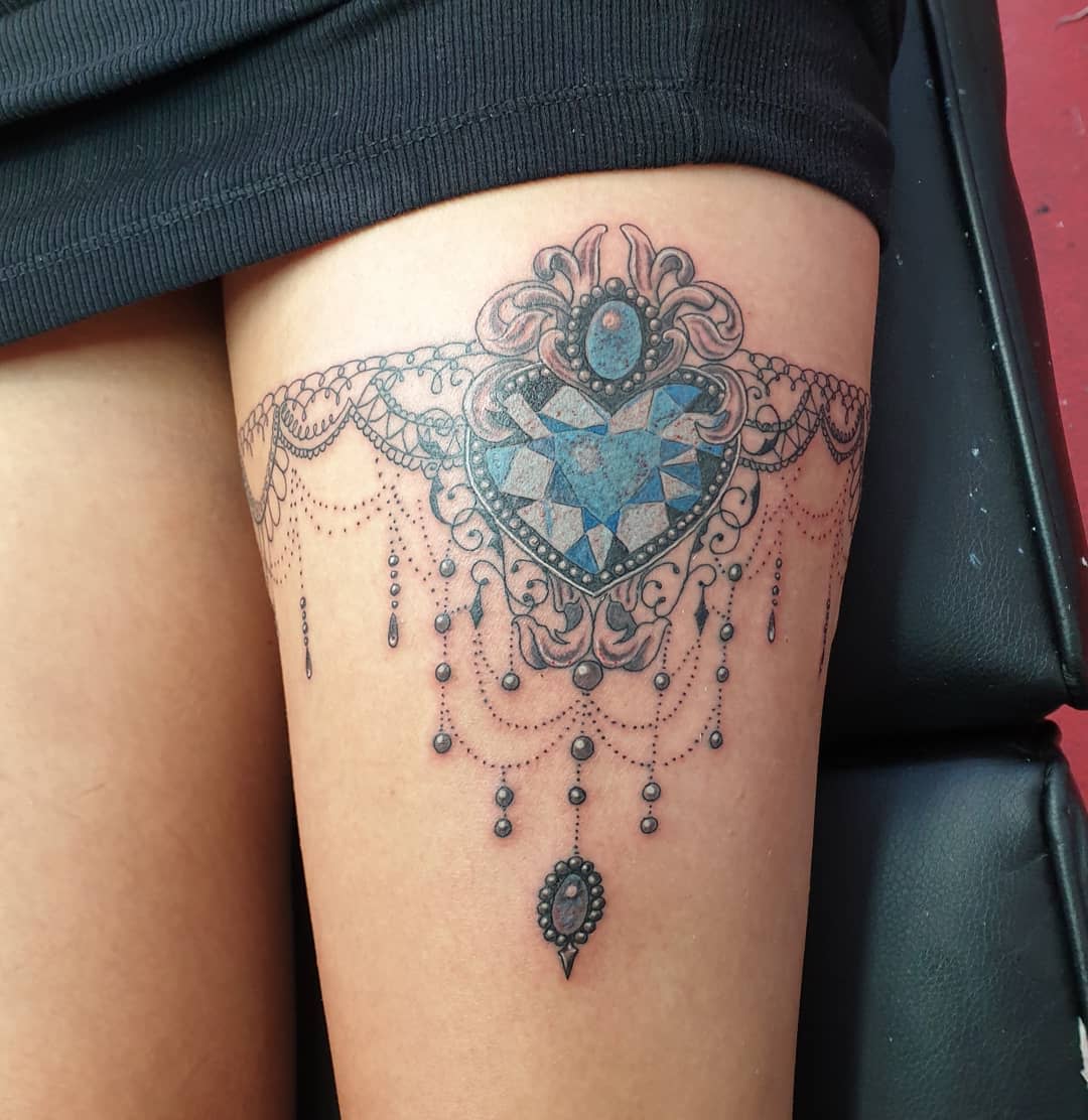 Intricate thigh tattoo with a gem-like heart design and hanging chandelier elements