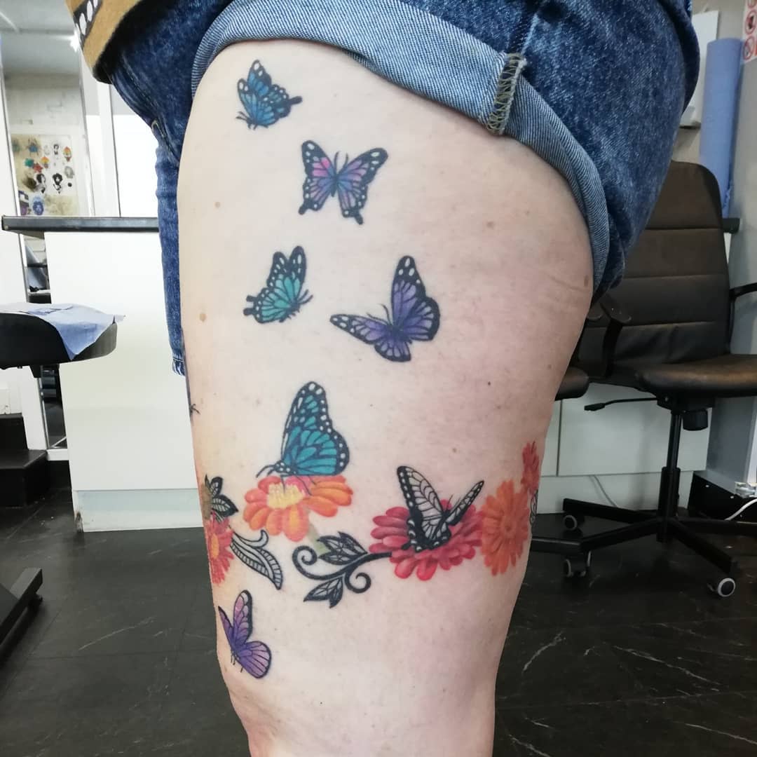 Tattoo of colorful butterflies and flowers on a thigh