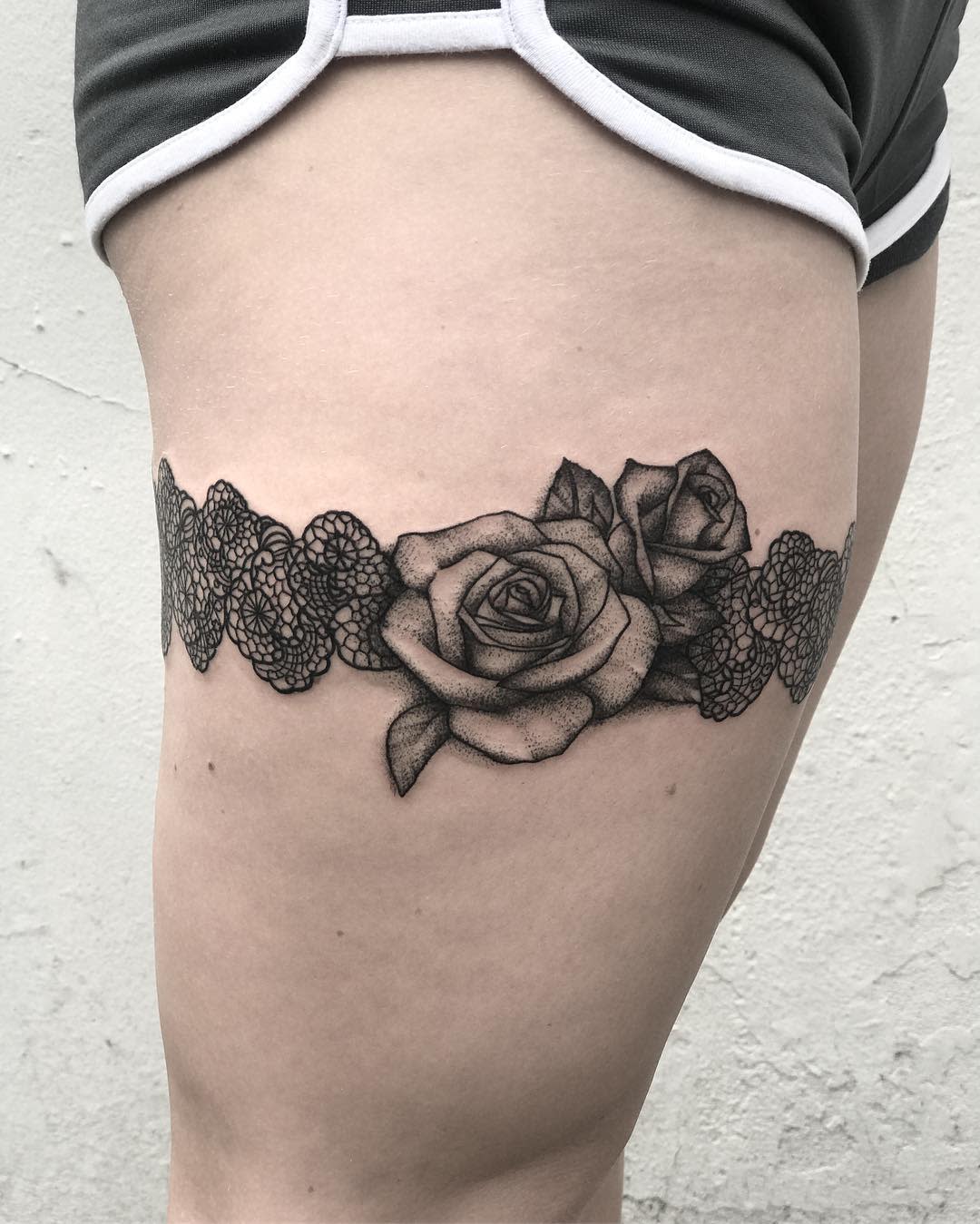 Leg tattoo featuring lace and roses wrapped around the upper thigh