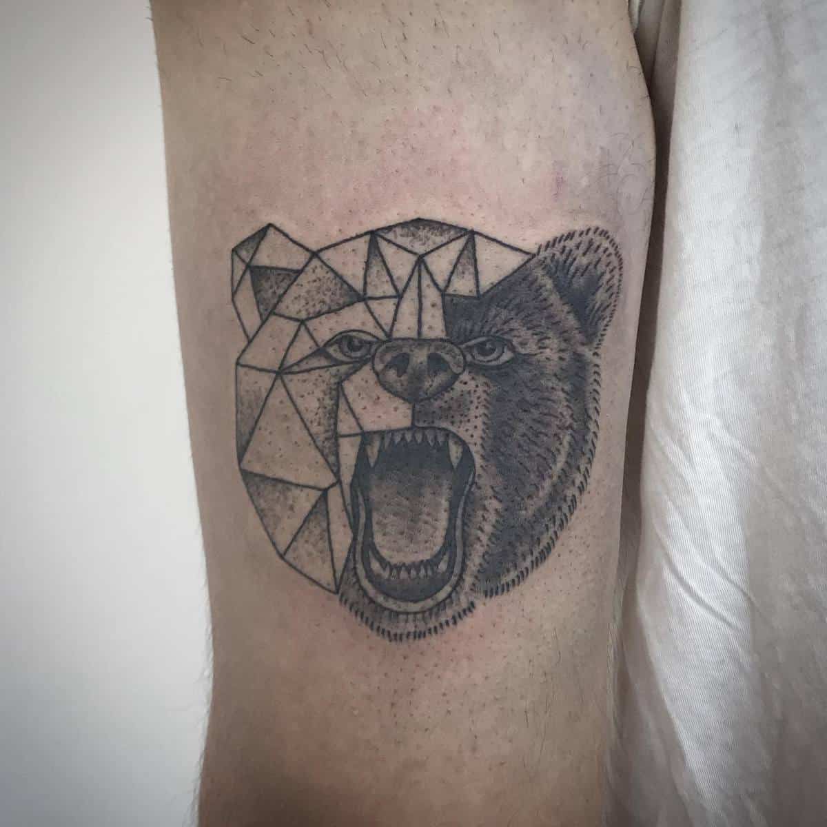 Tattoo of a roaring bear with geometric lines and realistic detailing on a person's arm