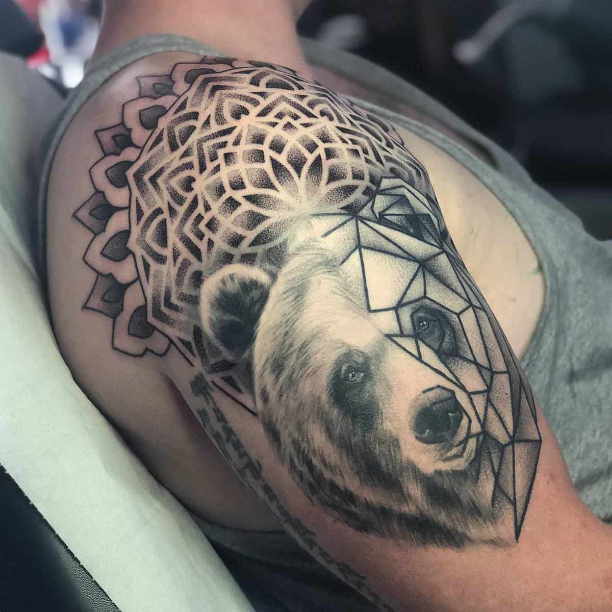 Tattoo of a bear with geometric shapes and a mandala design on a person's upper arm