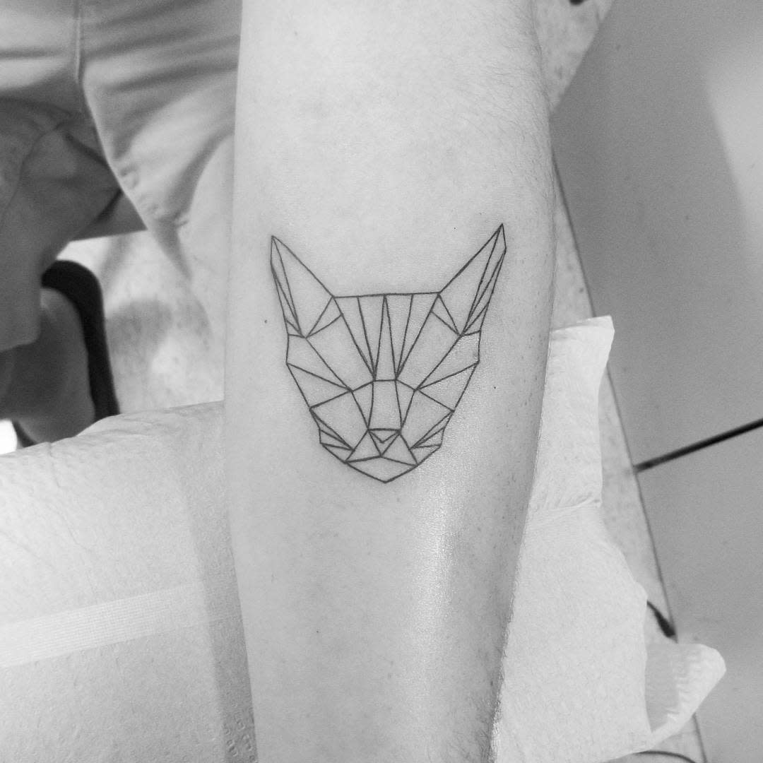 Geometric cat head design tattooed on a person's forearm highlighting the feline elegance in intricate lines and shapes