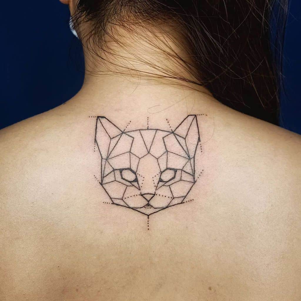 Geometric cat face tattoo on upper back of person with dark hair, highlighting feline characteristics