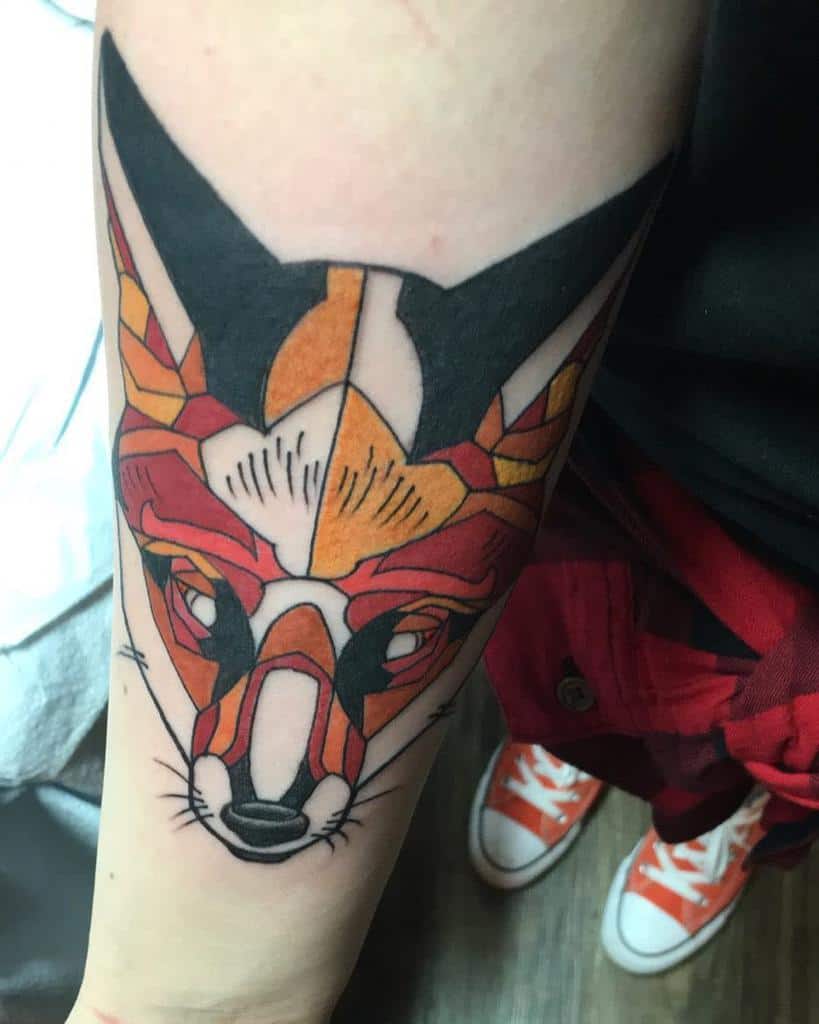 Forearm tattoo with a geometric fox design using vibrant orange, black, and white elements