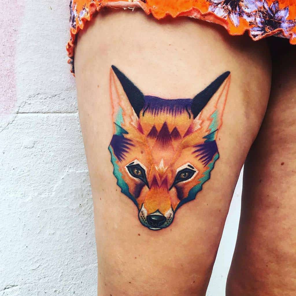 A colorful geometric wolf and fox tattoo on a person's upper thigh