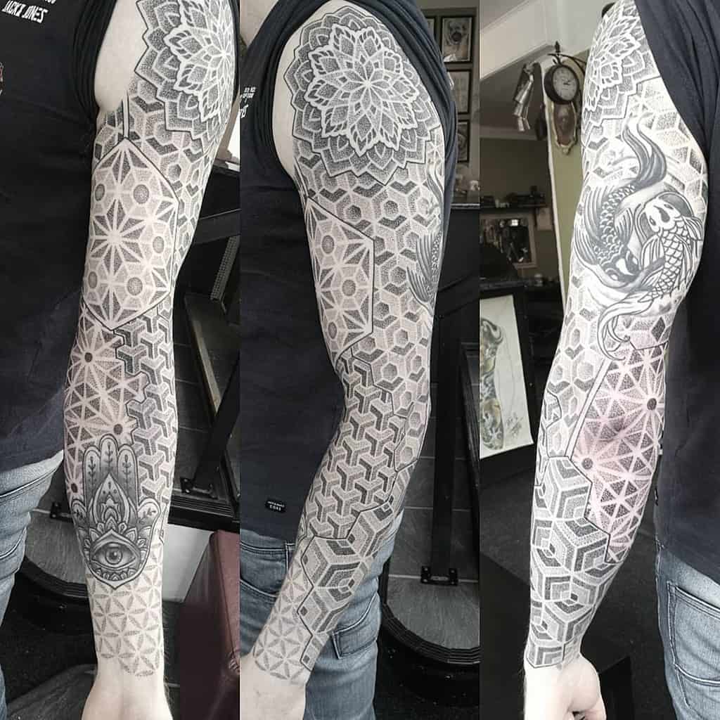 A geometric full sleeve tattoo featuring intricate patterns, mandala designs, and 3D cube shapes, with a Hamsa hand and eye symbol on the forearm