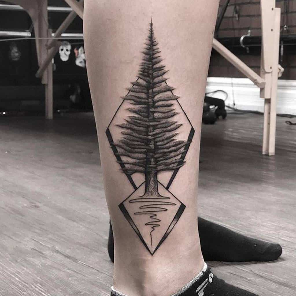 Leg tattoo featuring a geometric tree silhouette with mirrored water reflection inside a hexagonal frame