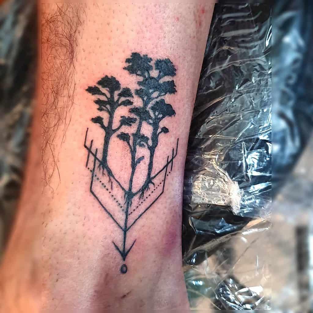 Tattoo of tree silhouettes with geometric lines on an arm