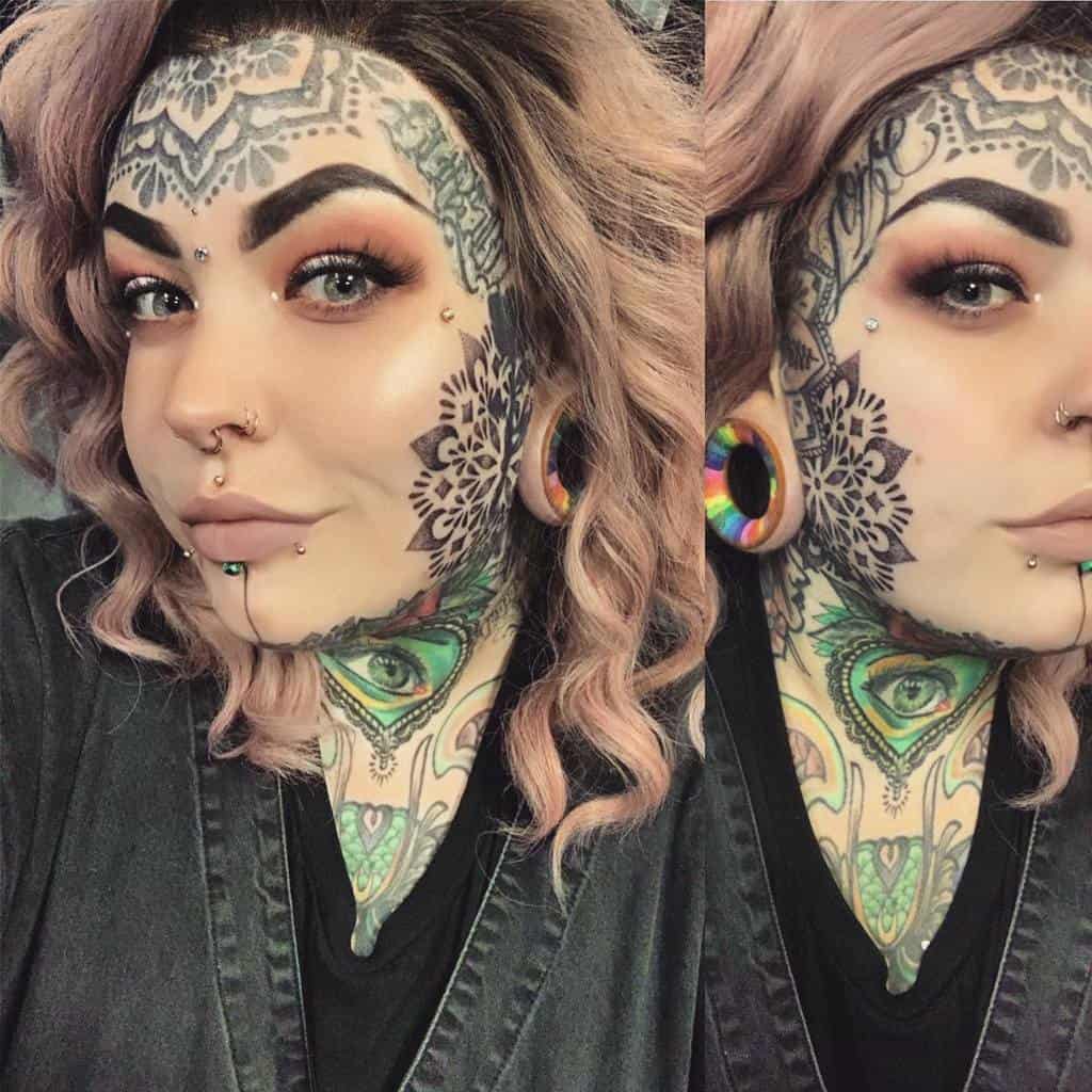 A woman with intricate mandala facial tattoos, rainbow plugs, piercings, bold makeup, and colorful neck tattoos