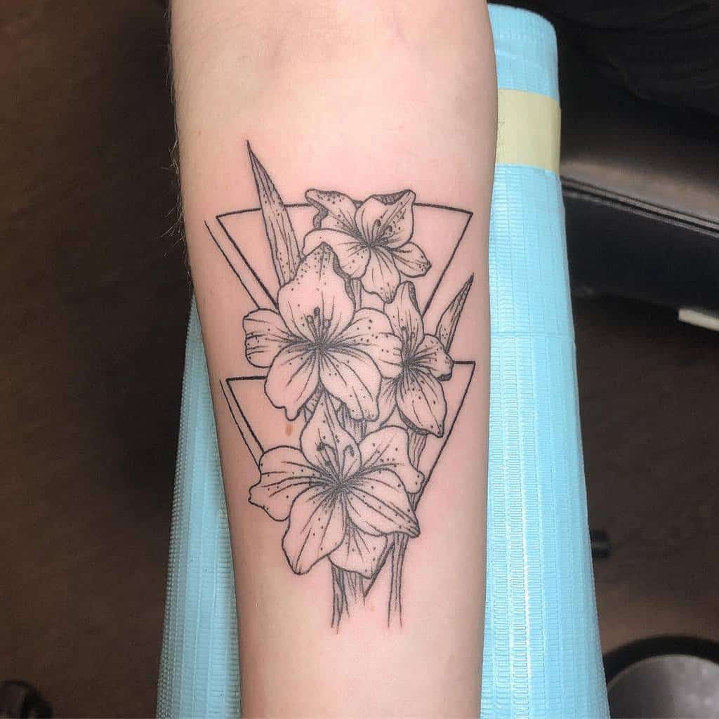 Outline tattoo of lilies and gladiolus framed by two overlapping triangles, on an arm