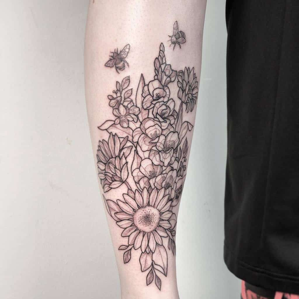 Black and white floral tattoo on a forearm featuring gladiolus blooms with bees flying above the flowers
