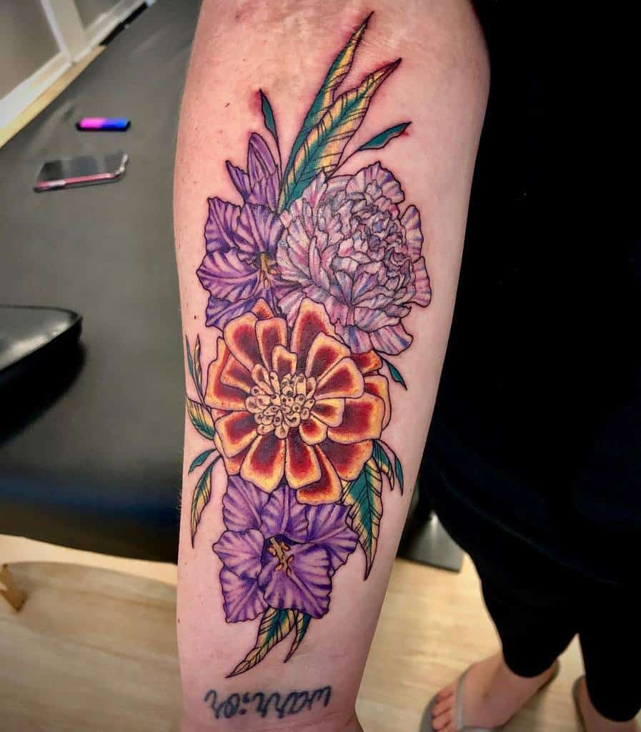 Colorful floral tattoo on forearm with vibrant purple and orange gladiolus flowers, and green leaves