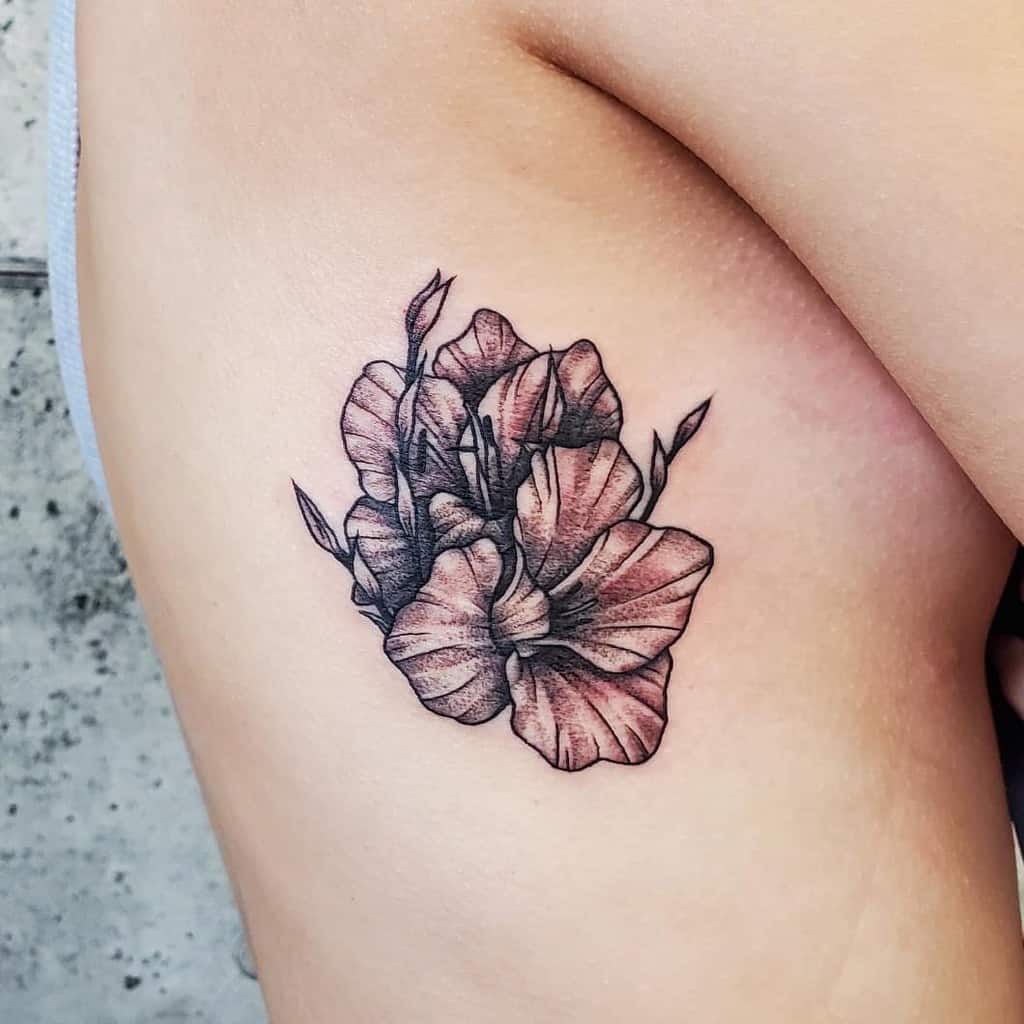 A black and grey gladiolus floral tattoo beautifully adorns a person's upper thigh