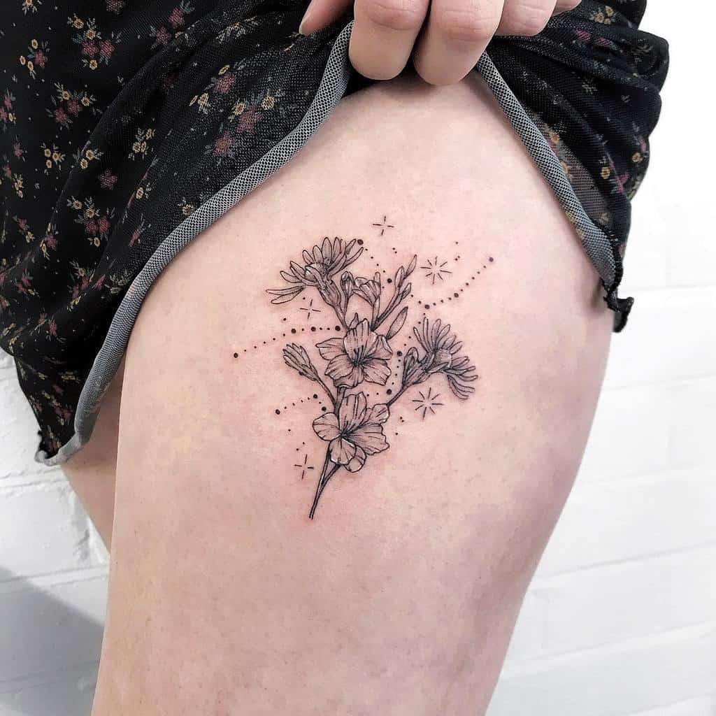 A person proudly displays a stunning floral tattoo featuring a gladiolus on their upper thigh