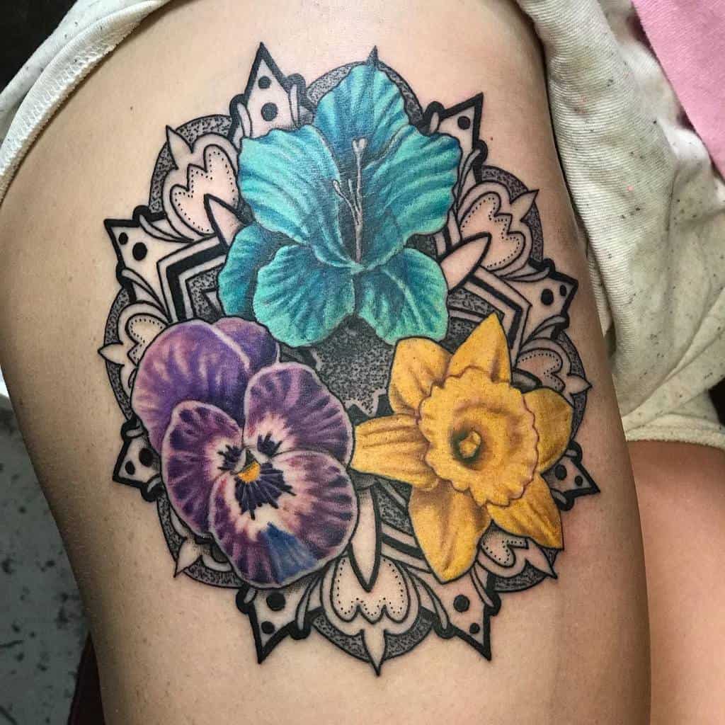 Colorful floral tattoo with gladiolus, blue, purple, and yellow flowers on a person's thigh