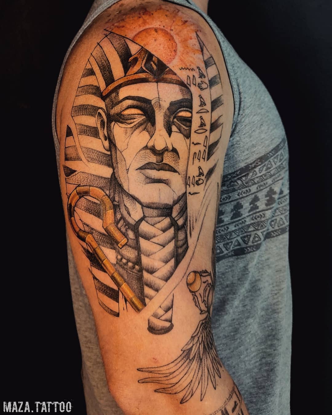 Pharaoh-themed tattoo on upper arm featuring an elaborate headdress and ankh symbol
