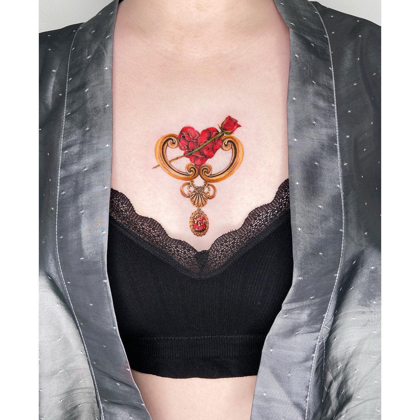 Decorative chest tattoo featuring red roses, gold accents, and a dangling jewel