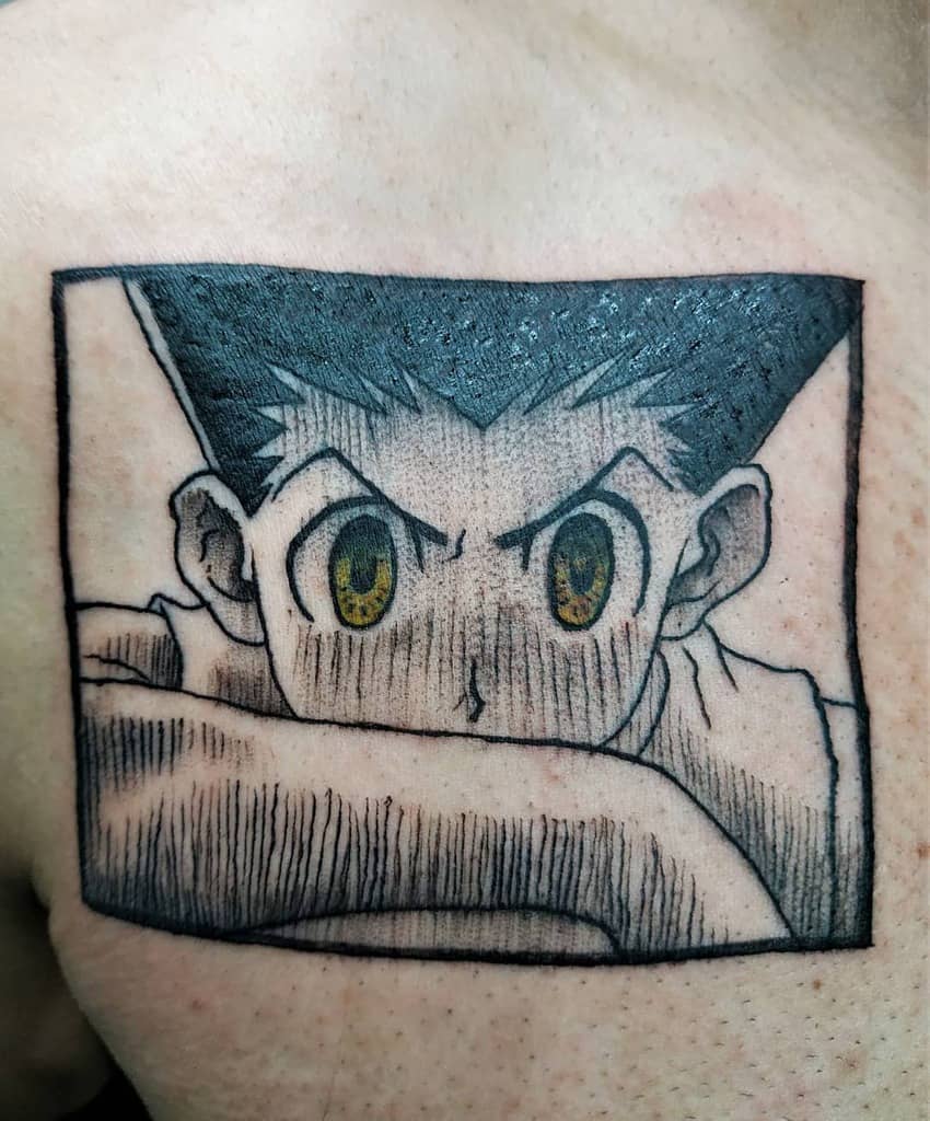 Black-and-grey tattoo of Gon Freecss from Hunter x Hunter, featuring intense yellow eyes and a focused expression in a framed design