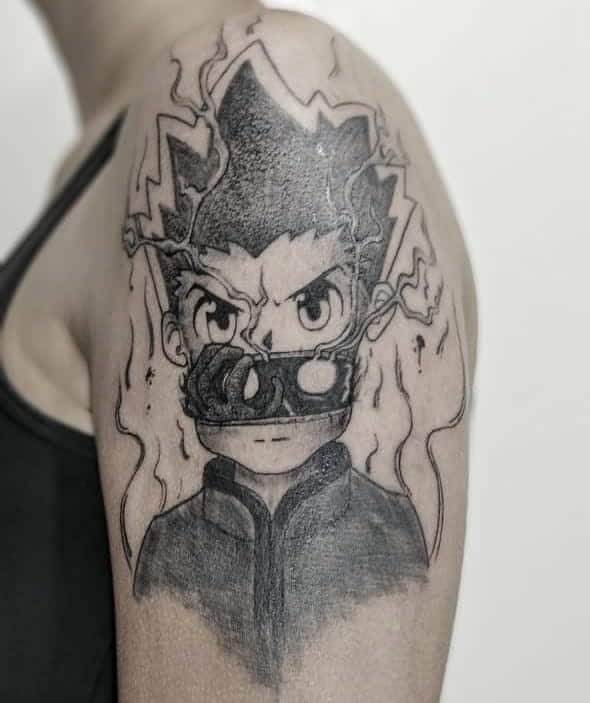 Intense black-and-grey tattoo of Gon Freecss from Hunter x Hunter, featuring a fiery aura and a determined expression on the upper arm