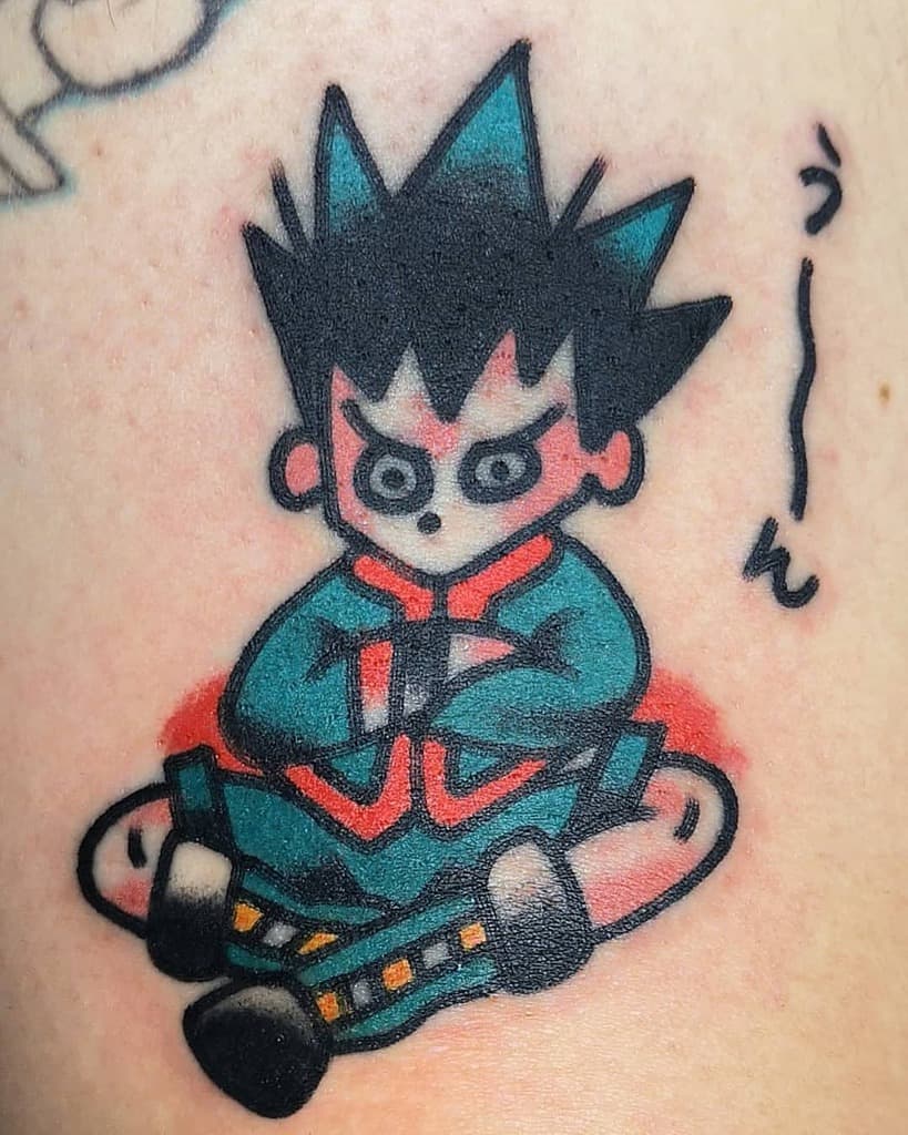 Playful and colorful tattoo of a chibi Gon Freecss from Hunter x Hunter, sitting cross-legged with a determined expression