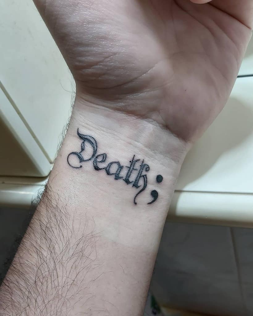 A wrist tattoo featuring the word "Death" followed by a semicolon