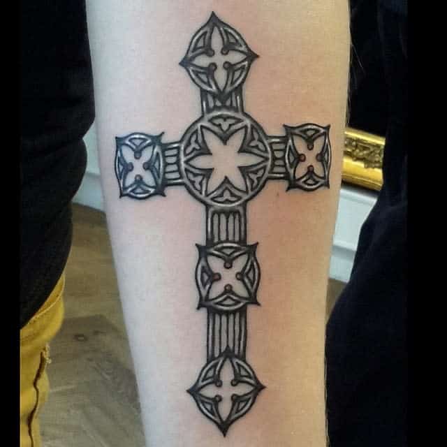 A Celtic-style tattoo showcases a detailed cross entwined with intricate knot patterns