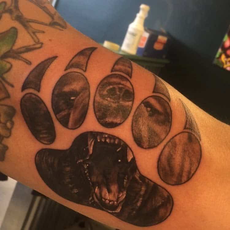 Arm tattoo with a large bear paw, realistic bear faces intricately designed inside each pad and claw segment