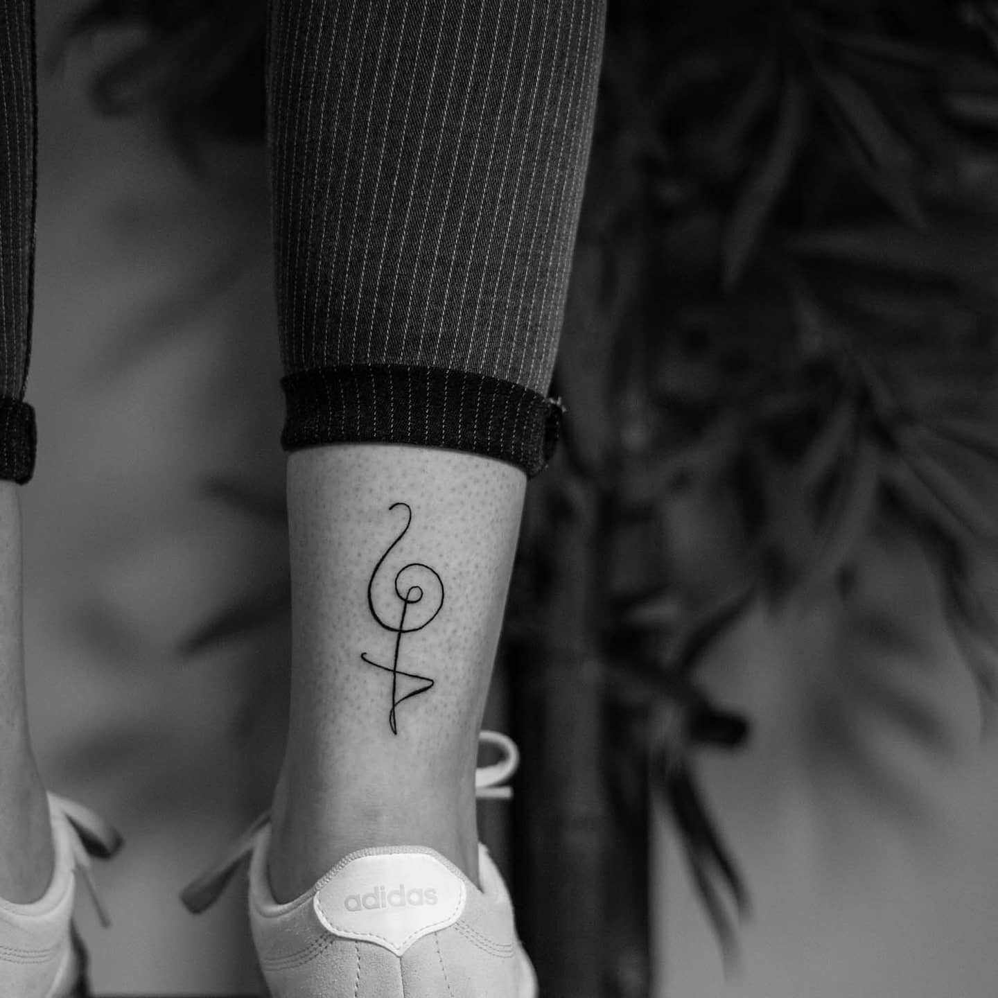 Minimalist Hakuna Matata tattoo on an ankle, combining symbols and abstract design