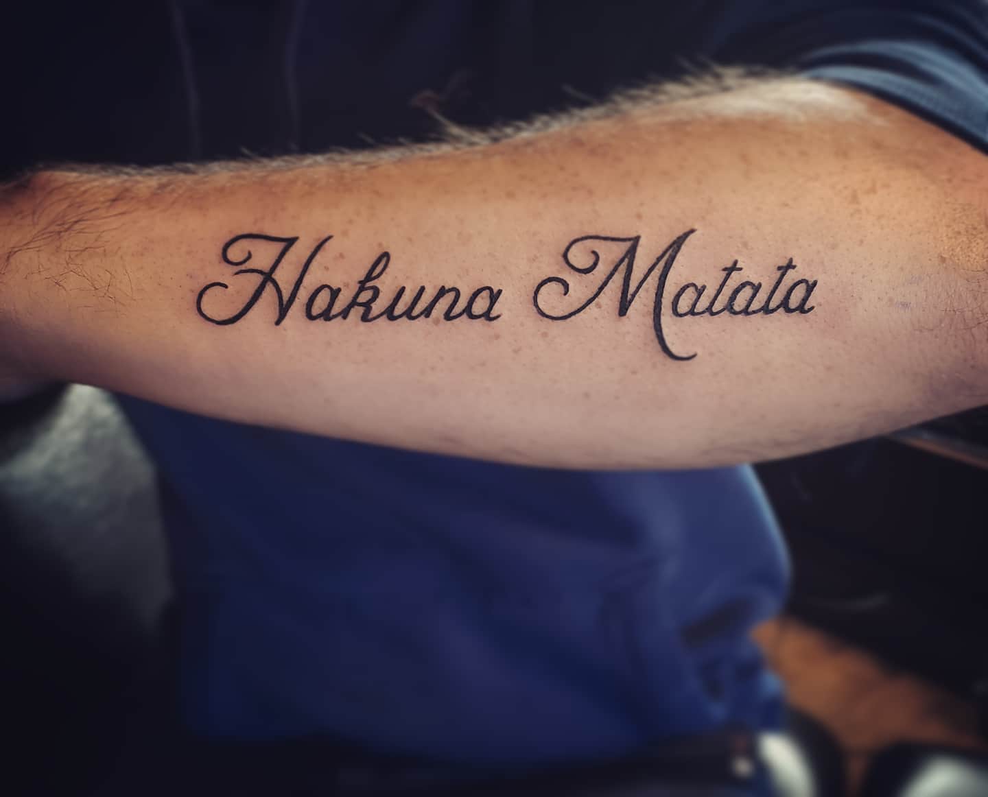 Tattoo on forearm that reads "Hakuna Matata" in cursive script