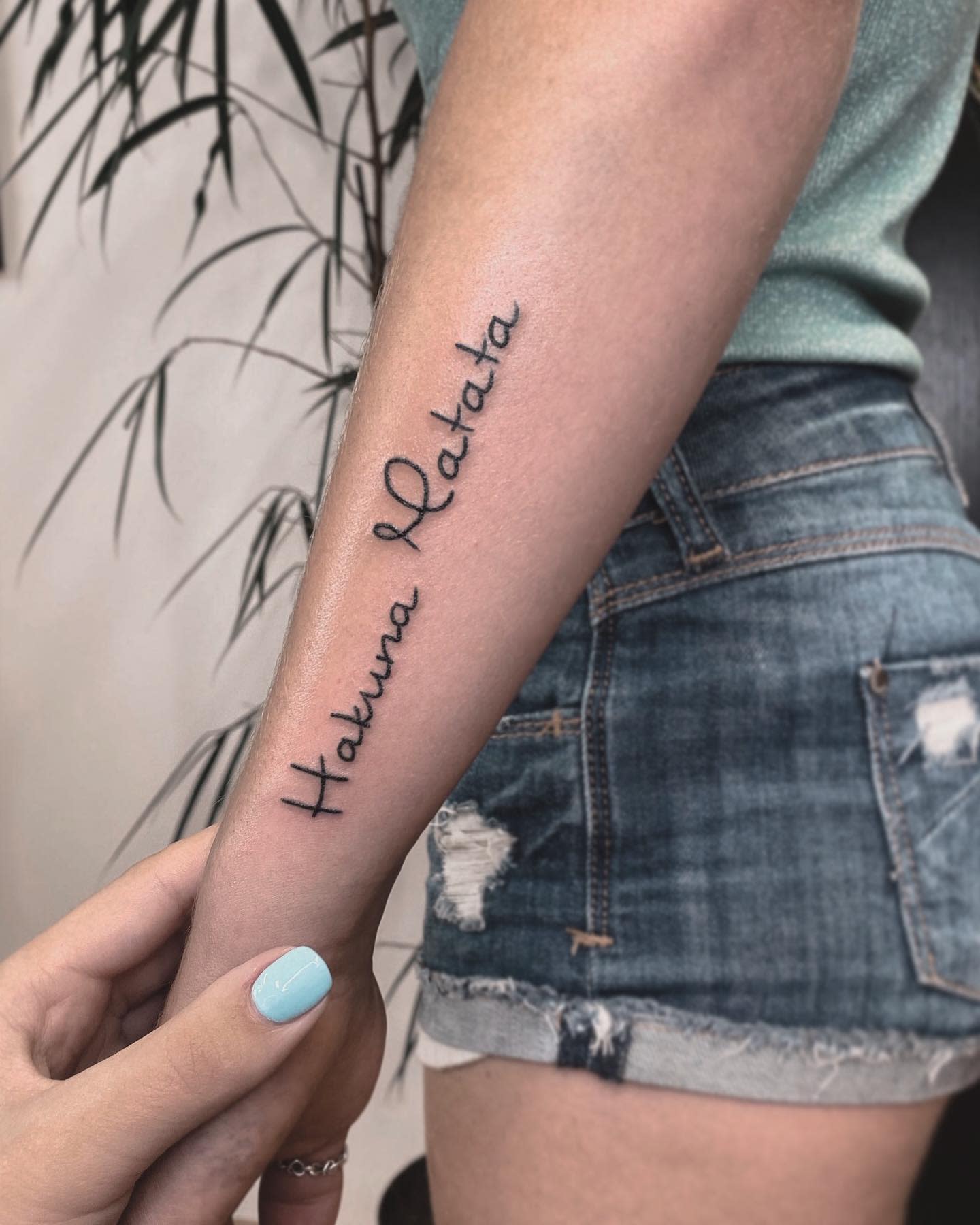 Forearm tattoo reading "Hakuna Matata"