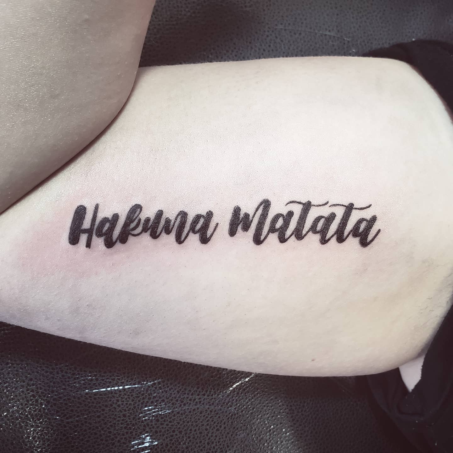 Tattoo o a bicep with the text "Hakuna Matata" in cursive font