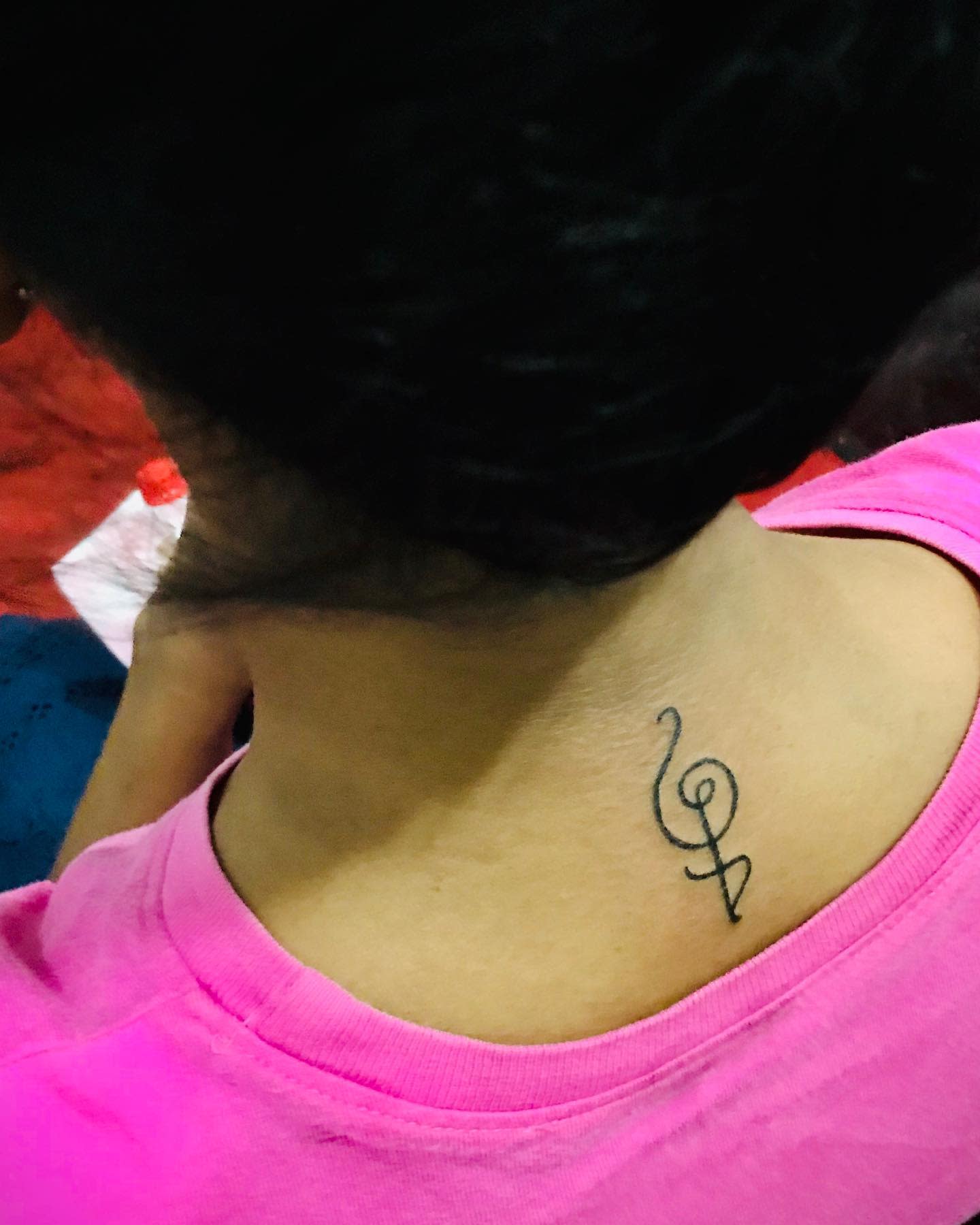 A small Hakuna Matata and symbol tattoo on the back of the neck