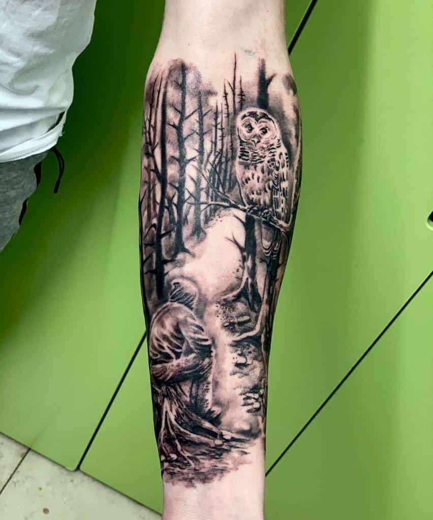 Forearm tattoo of a forest scene with a hooded figure and a perched owl