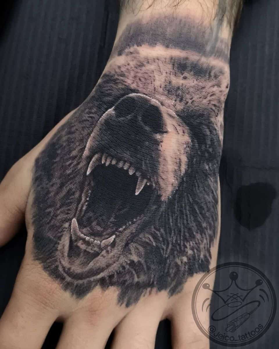 Tattoo of a roaring bear on the back of a person's hand capturing raw strength and primal energy