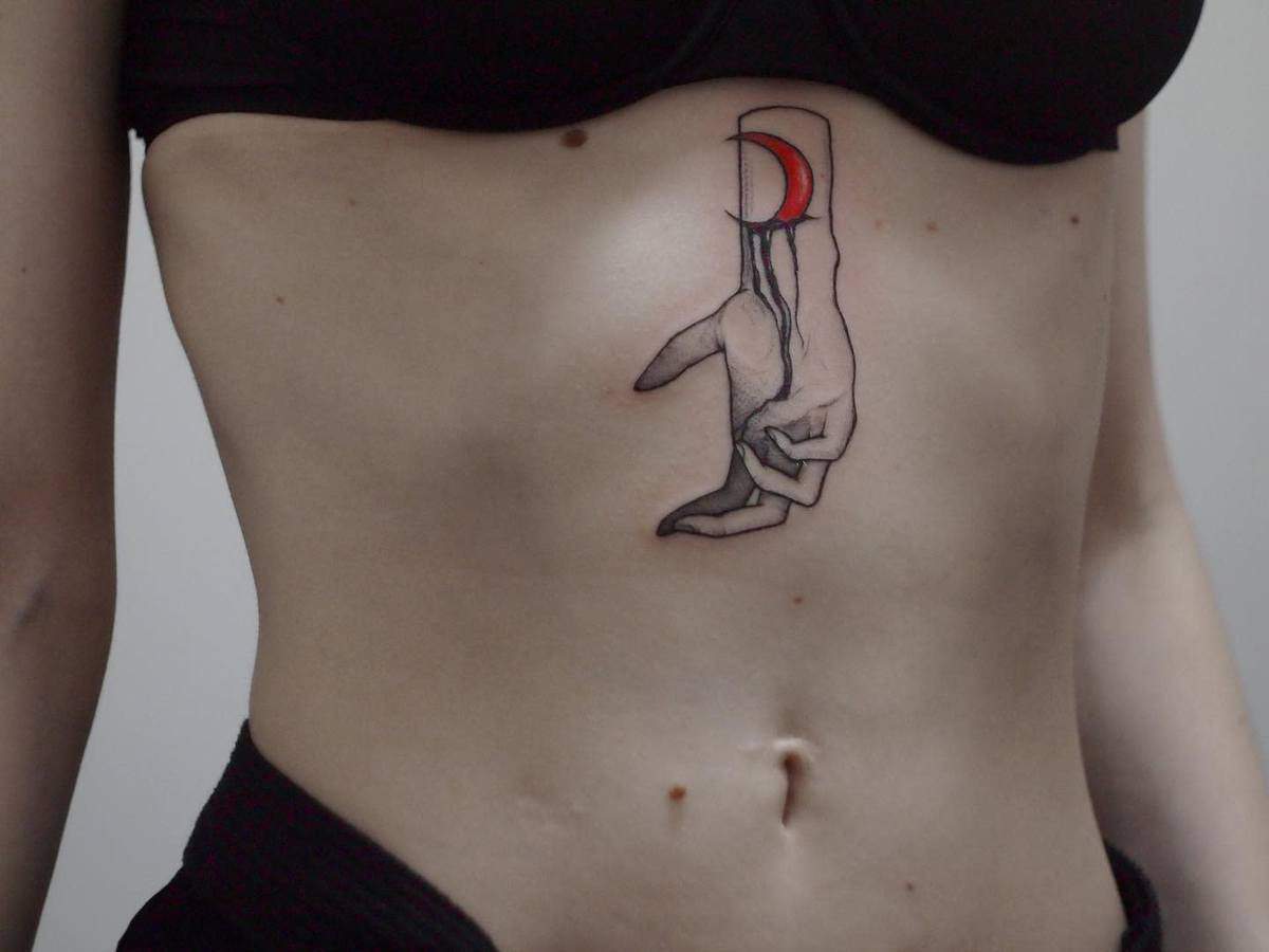 Tattoo of an abstract hand and red moon on a lower abdomen