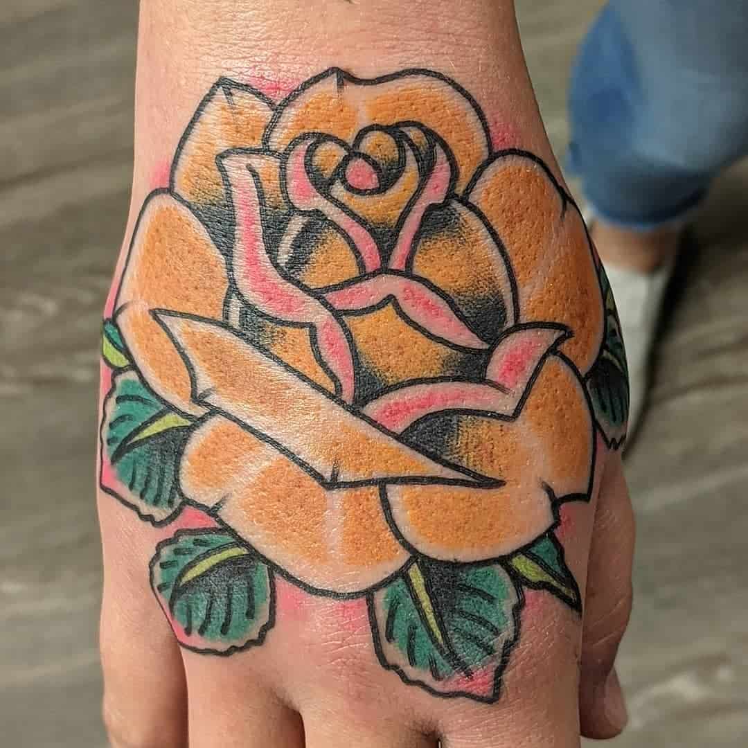 Hand tattoo of a yellow rose with green leaves