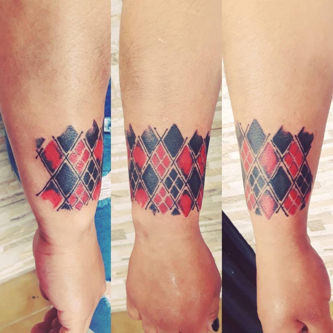 Forearm tattoo featuring a red and black argyle pattern with sketchy black accents