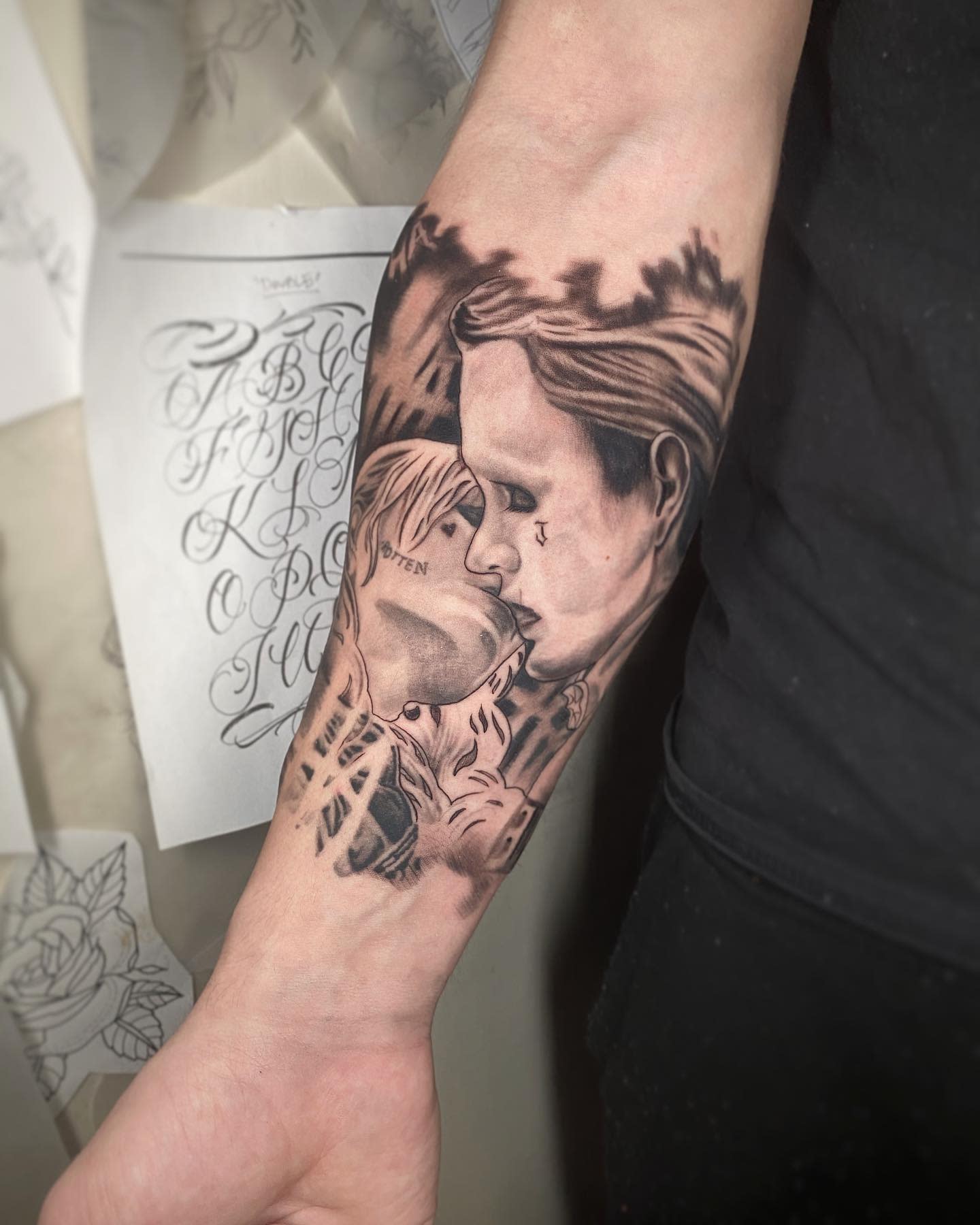 Realistic tattoo of Harley Quinn and Joker from 'Suicide Squad' sharing a kiss on a forearm