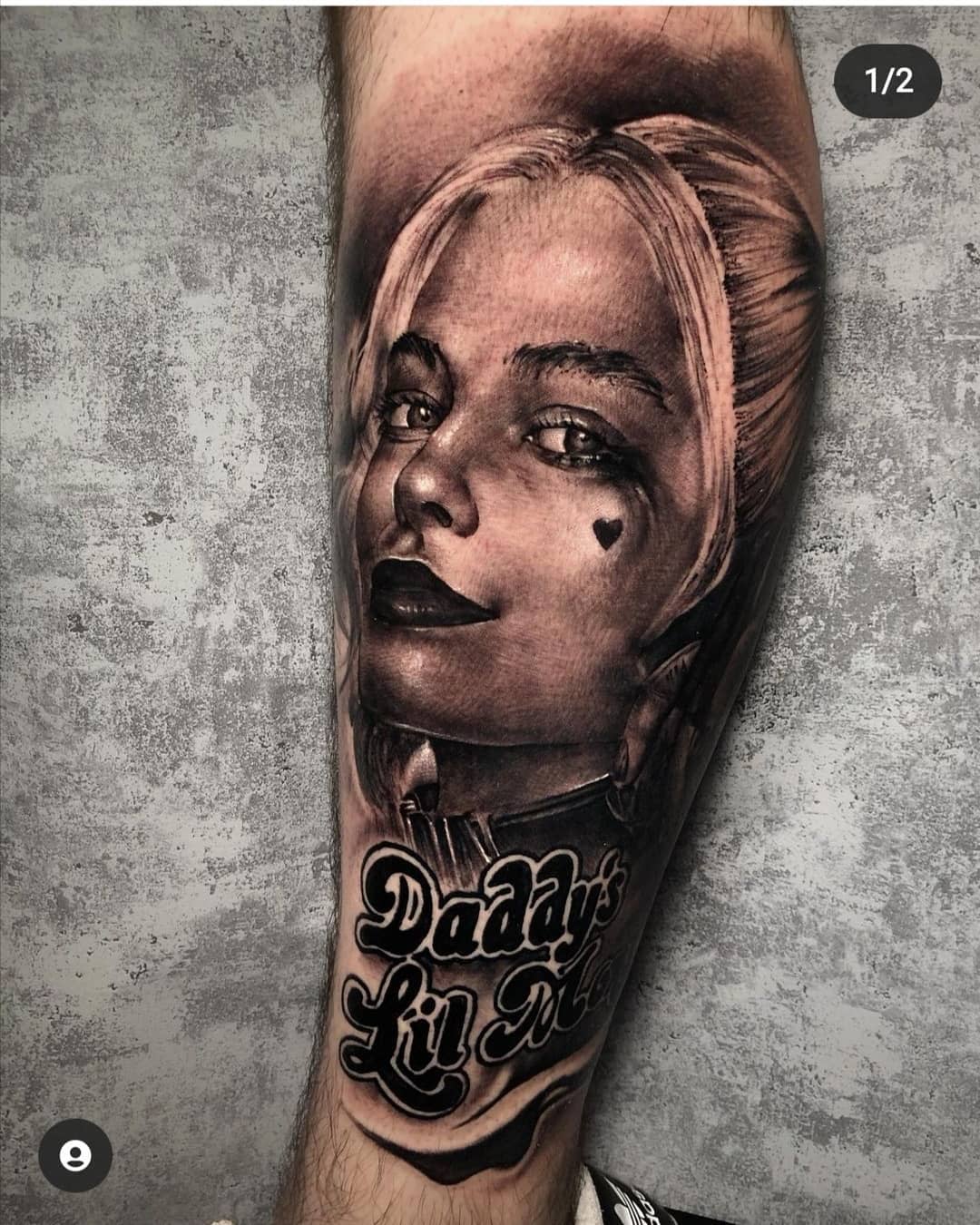 Realistic tattoo of Harley Quinn's face with a heart tattoo under her eye, accompanied by the phrase 'Daddy's Lil Monster' on the forearm