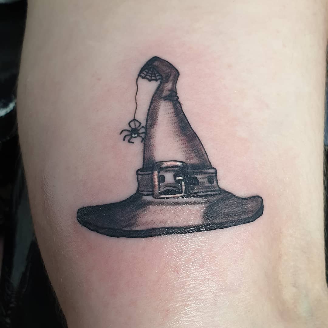 Tattoo of a witch hat with a small spider hanging from the tip