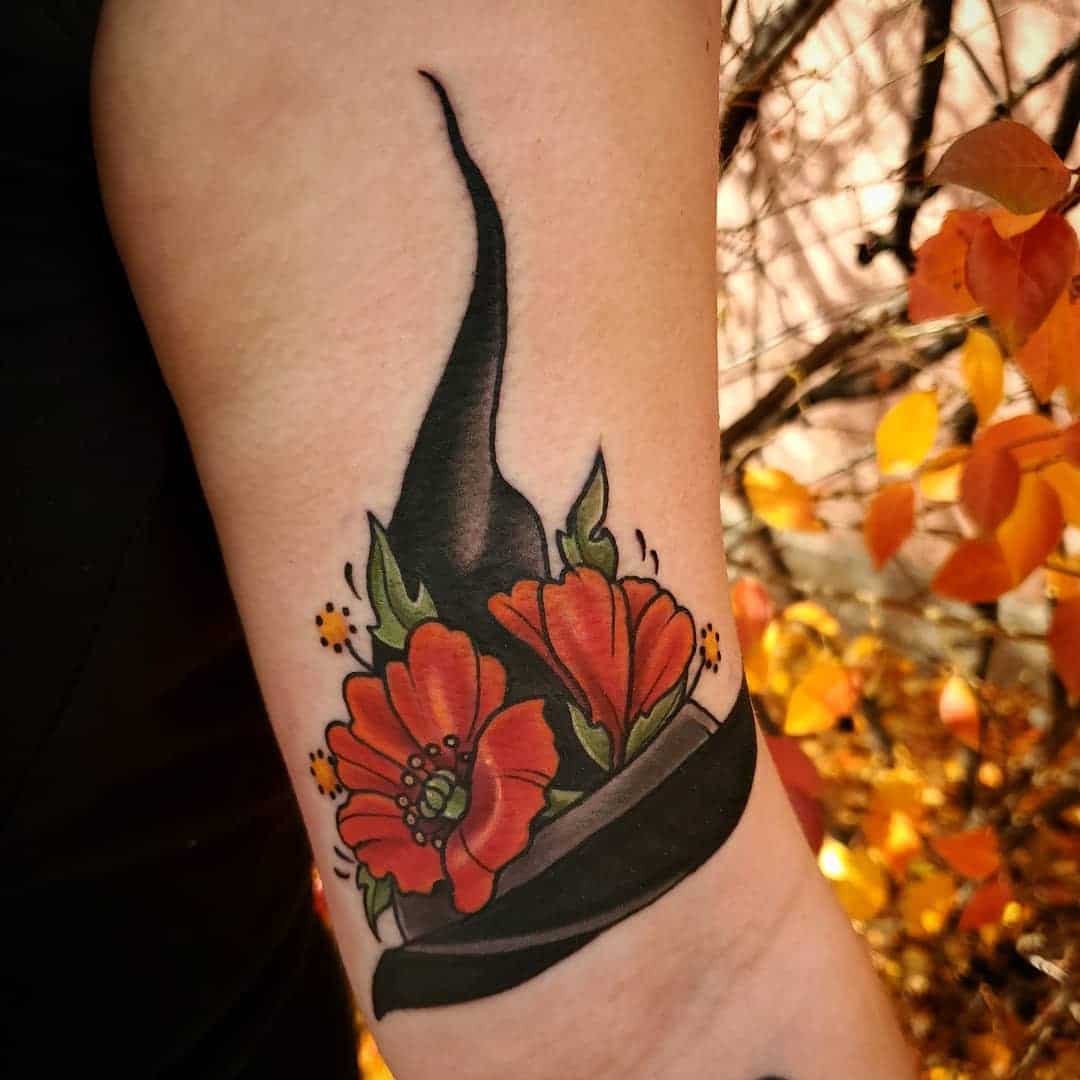 Tattoo of a witch hat with red flowers