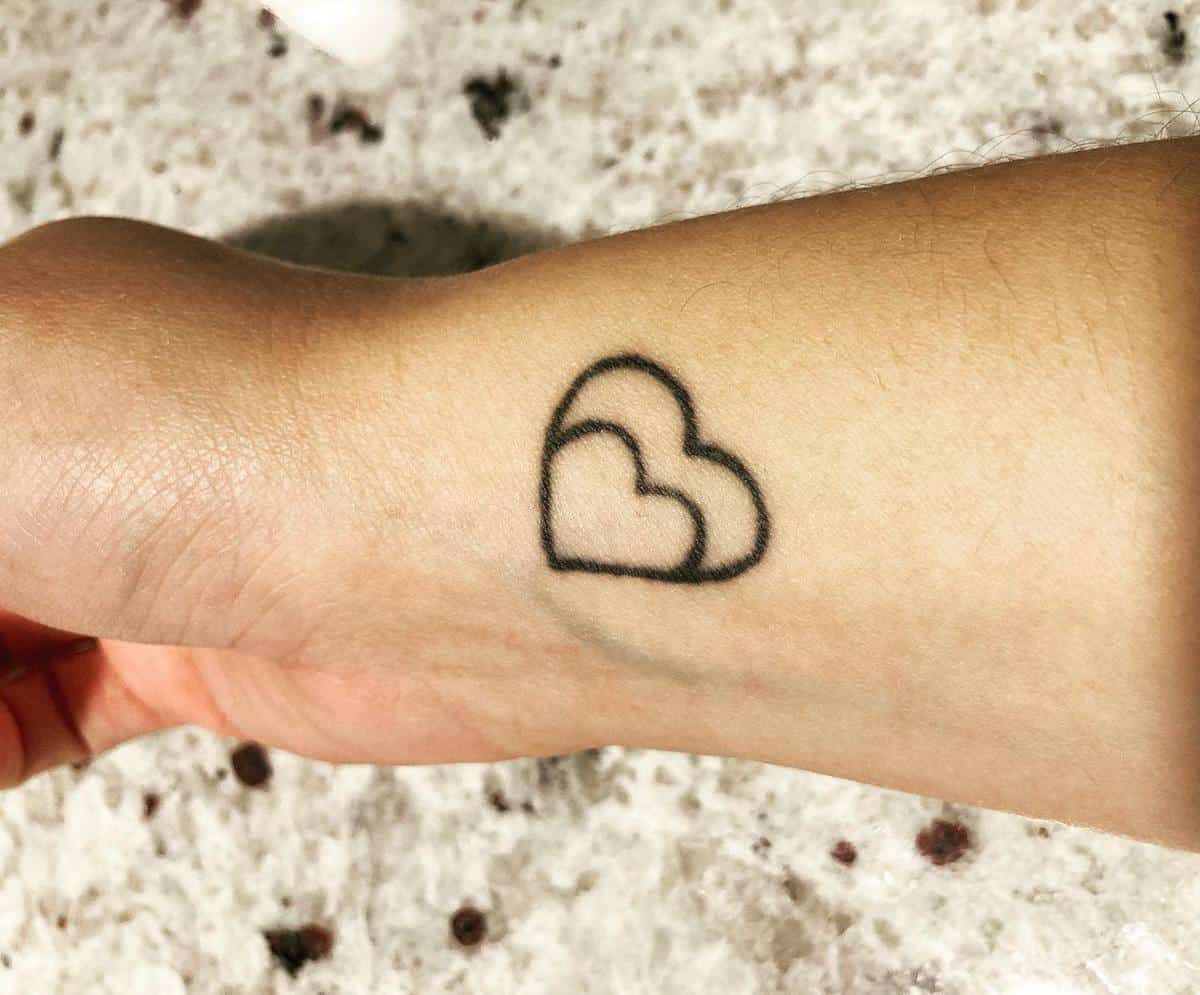A tattoo of two intertwined hearts on a forearm