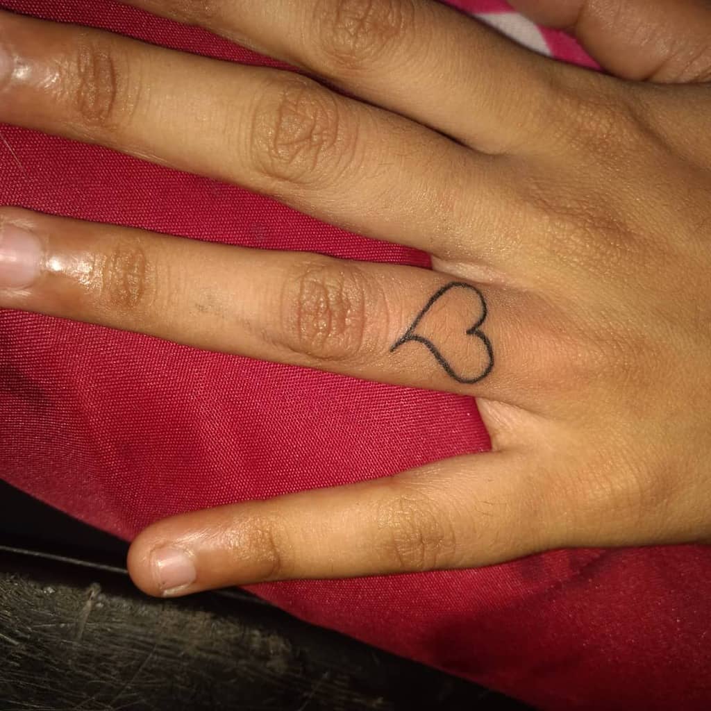 Hand with a small heart tattoo on the ring finger