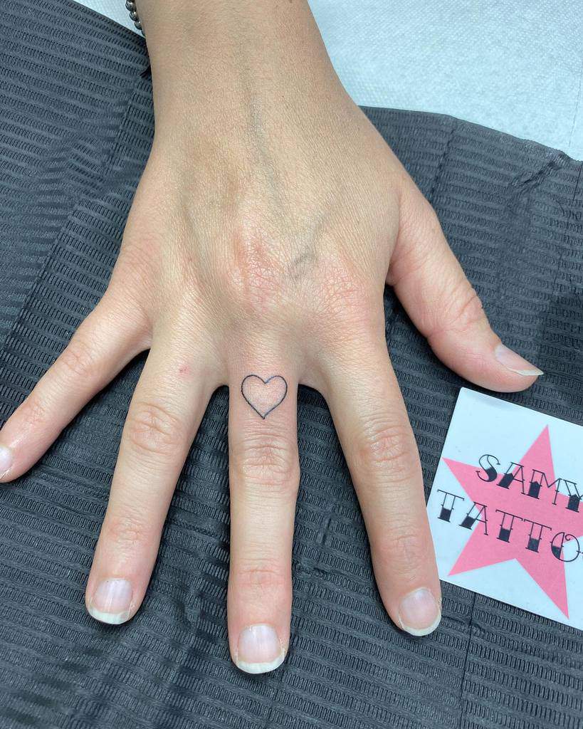 Heart outline tattoo on the middle finger
