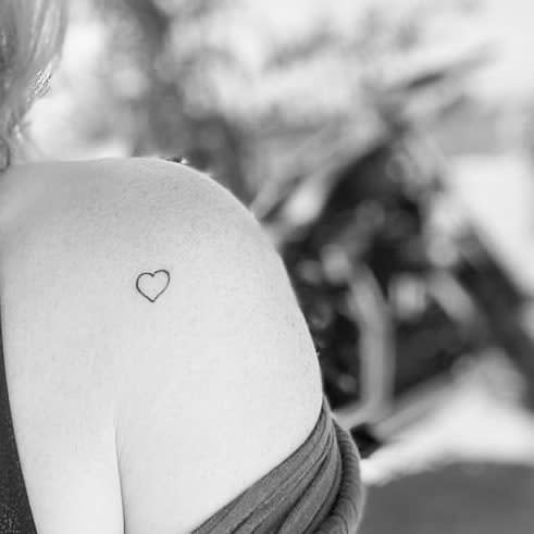 Small heart outline tattoo on a woman's shoulder