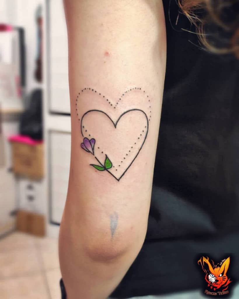 Heart tattoo with another dotted outline heart and purple flower on an upper arm